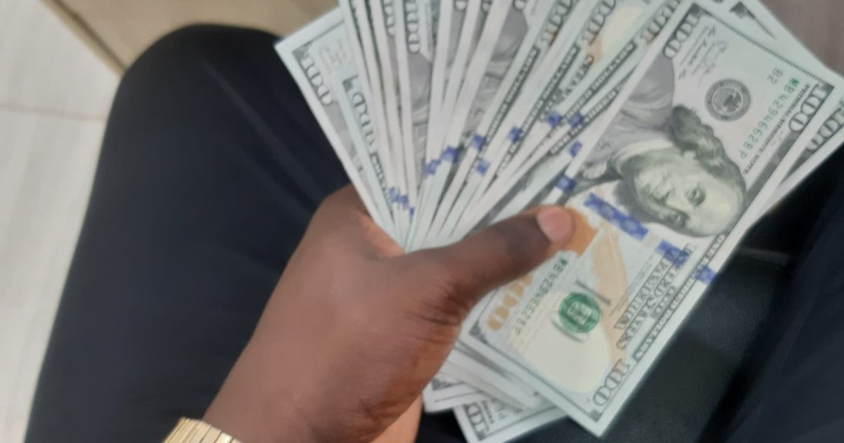 ہاتھ میں امریکی سو ڈالر کے نوٹ — dollar rate today کے مطابق انٹربینک میں ڈالر 276.87 روپے