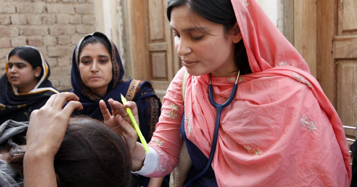 پاکستان میں موبائل ہیلتھ کلینک پر مریض کا معائنہ کرتی خاتون ڈاکٹر — clinic on wheels ajk صحت سہولت